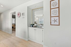 A hallway with a white door, a mirror, and a wall with framed artwork. - Tilghman Shores I6- 2 Bedroom- Pool, Hot Tub (North Myrtle Beach)