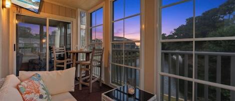A sunroom with a sofa, chairs, a table, and large windows.