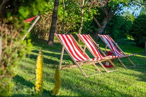 Two wooden lounge chairs with red and white striped cushions, positioned on a grassy lawn with trees in the background. - Comfortable holiday home with a fireplace, Bobolin (Bobolin)
