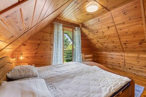 A cozy bedroom with a sloped ceiling, a single bed, a nightstand, and a window with curtains. - Comfortable holiday home with a fireplace, Bobolin (Bobolin)