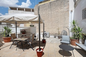 An outdoor patio with a table and chairs, a hanging chair, and potted plants. - Apartment 'Casa Itria, Acqua' with Private Terrace, Wi-Fi and Air Conditioning (Martina Franca)