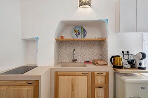 Een kleine keuken met een spoelbak, een waterkoker en een broodrooster.