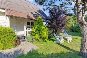 A single-story building with a porch, a small tree, and two Adirondack chairs. - Large and comfortable holiday home with a terrace (Bobolin)