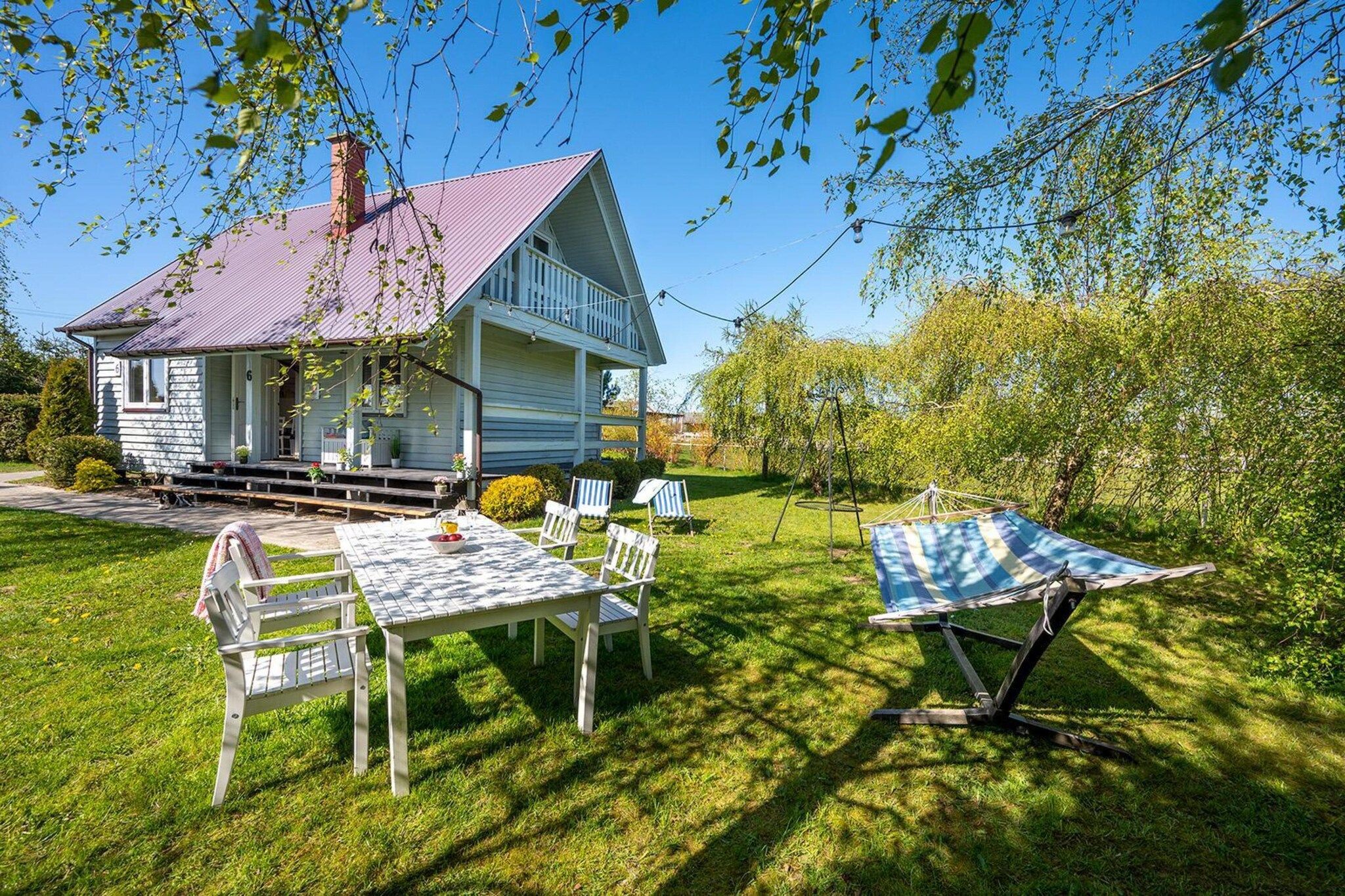 A house with a porch, a table with chairs, and a hammock.