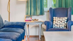 A room with a blue sofa, a matching armchair, a small table with books, and a lamp. - Comfortable holiday home with a fireplace (Bobolin)
