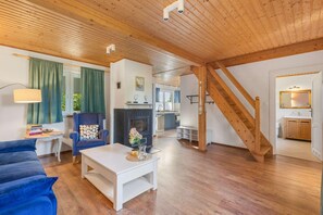 A spacious living area with a fireplace, a staircase, and a kitchen visible in the background. - Comfortable holiday home with a fireplace (Bobolin)