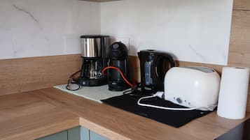Eine Küche mit Kaffeemaschine, Toaster und einer Küchenrolle auf der Arbeitsfläche.