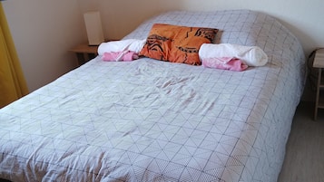 Ein Bett mit einem gemusterten Überwurf, Kissen und einem Nachttisch mit Lampe.