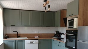A kitchen with green cabinets, a dishwasher, a microwave, and a refrigerator. - Single-family home (Sarlat-la-Canéda)