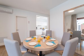 A dining area with a round table set for four, equipped with plates, cutlery, and a pitcher of orange juice. - Villa Omura 16 - Three Bedroom Villa, Sleeps 6 (Playa Blanca)
