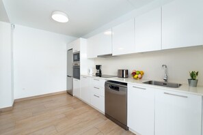 A modern kitchen with white cabinets, stainless steel appliances, a dishwasher, and a fruit bowl on the counter. - Villa Omura 16 - Three Bedroom Villa, Sleeps 6 (Playa Blanca)