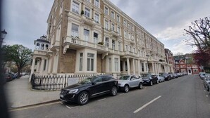 Um edifício de vários andares com estilo arquitetônico clássico, apresentando uma fachada simétrica com janelas uniformemente espaçadas e uma entrada central.
