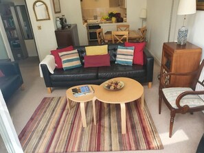 Ein Wohnzimmer mit einem schwarzen Sofa, einem Couchtisch und einem Streifenmuster-Teppich.