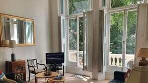 Uma sala de estar com televisão, sofá, poltrona e mesa de centro.