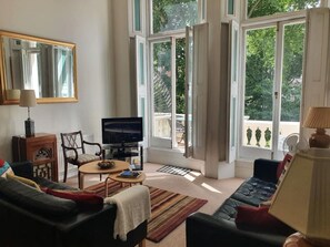 Ein Wohnzimmer mit Fernseher, einer Couch, einem Sessel und einem Couchtisch.
