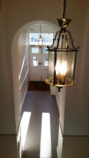 A hallway with a hanging lantern and a door at the end. - 2 bedroom Kensington apartment with terrace and usage of large gardens (London)