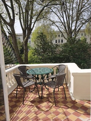 Ein Balkon mit kariertem Boden, einem runden Tisch und vier Stühlen.