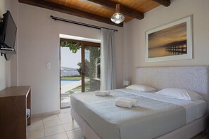 Quarto de hotel com cama, televisão, pintura e vista para a piscina e paisagem.