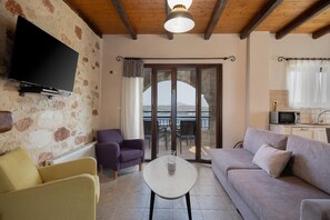 Uma sala de estar com sofá, poltronas, televisão e varanda com vista.