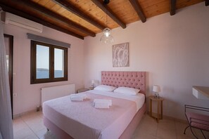 Ein Schlafzimmer mit einem großen Bett, einem Fenster mit Ausblick, einer Heizung und einer Holzbalkendecke.