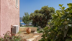 A building with a pink exterior, a large terracotta pot, and a tree in the foreground. - Villa Koule - Three Bedroom Villa, Sleeps 6 (Kalami)
