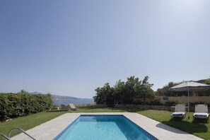 Ein Schwimmbecken mit freiem Blick auf das Meer und die entfernten Berge.