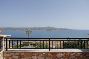 Ein Balkon mit Steinmauer und Metallgeländer, der auf ein Gewässer mit einem entfernten Berg blickt.