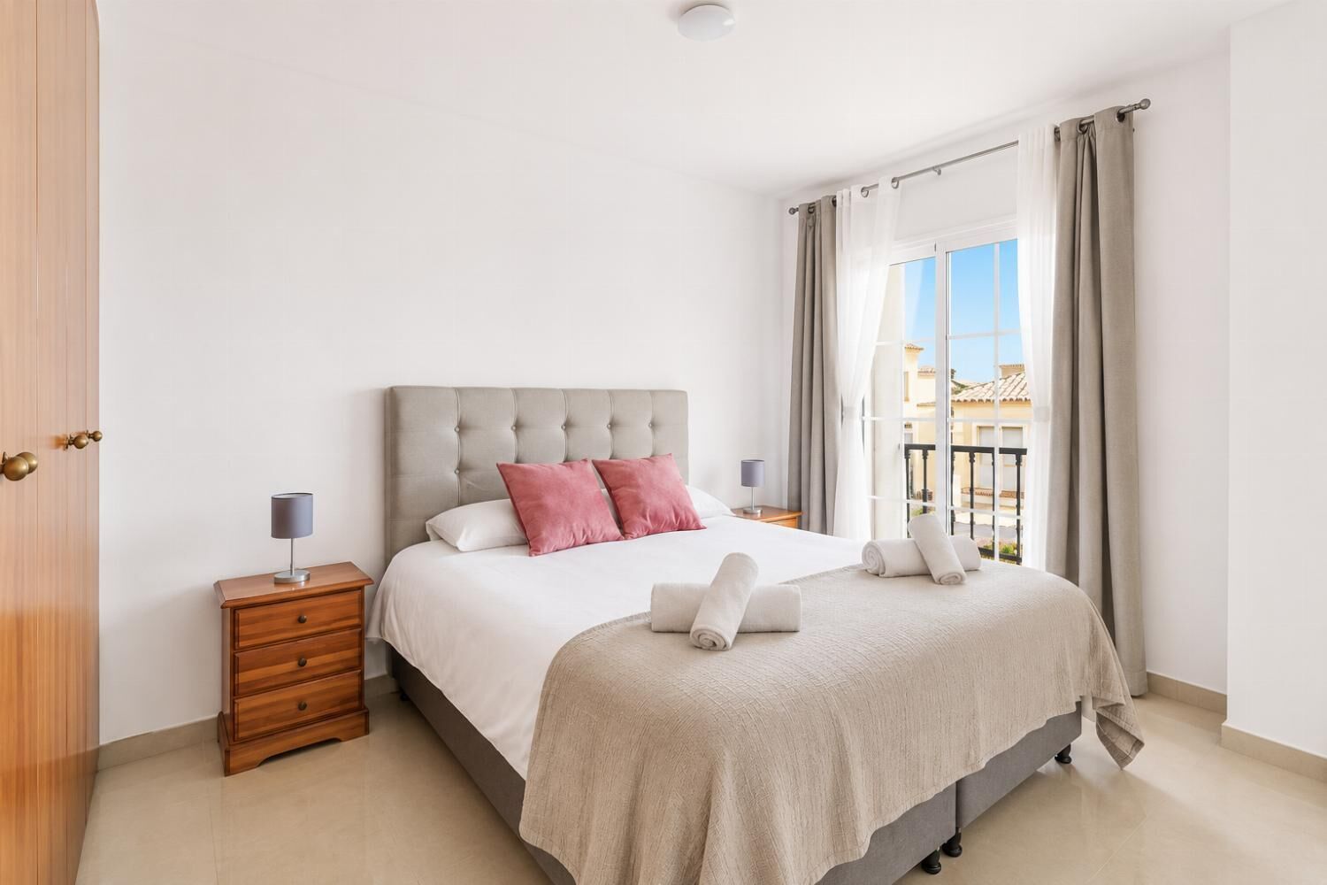 Una camera d'albergo con un letto, comodini, vista sull'esterno e un balcone.