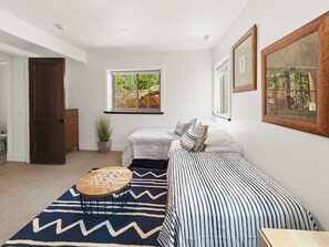 A bedroom with two beds, a window, a door, a plant, and a small table. - Family Neighborhood Nestled In Nature (Park City)