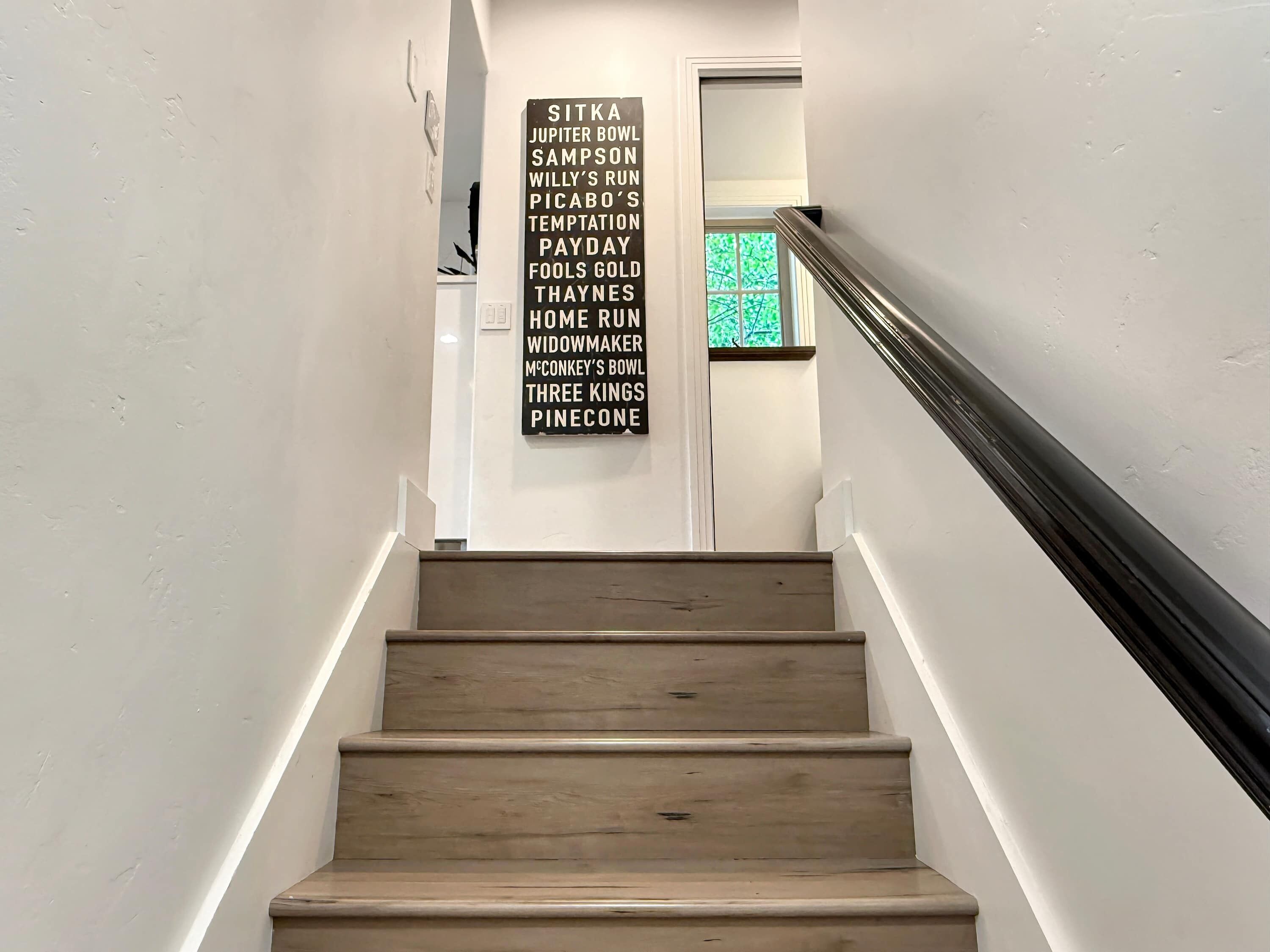 Una escalera con barandilla y un cartel en la pared que enumera varios nombres.