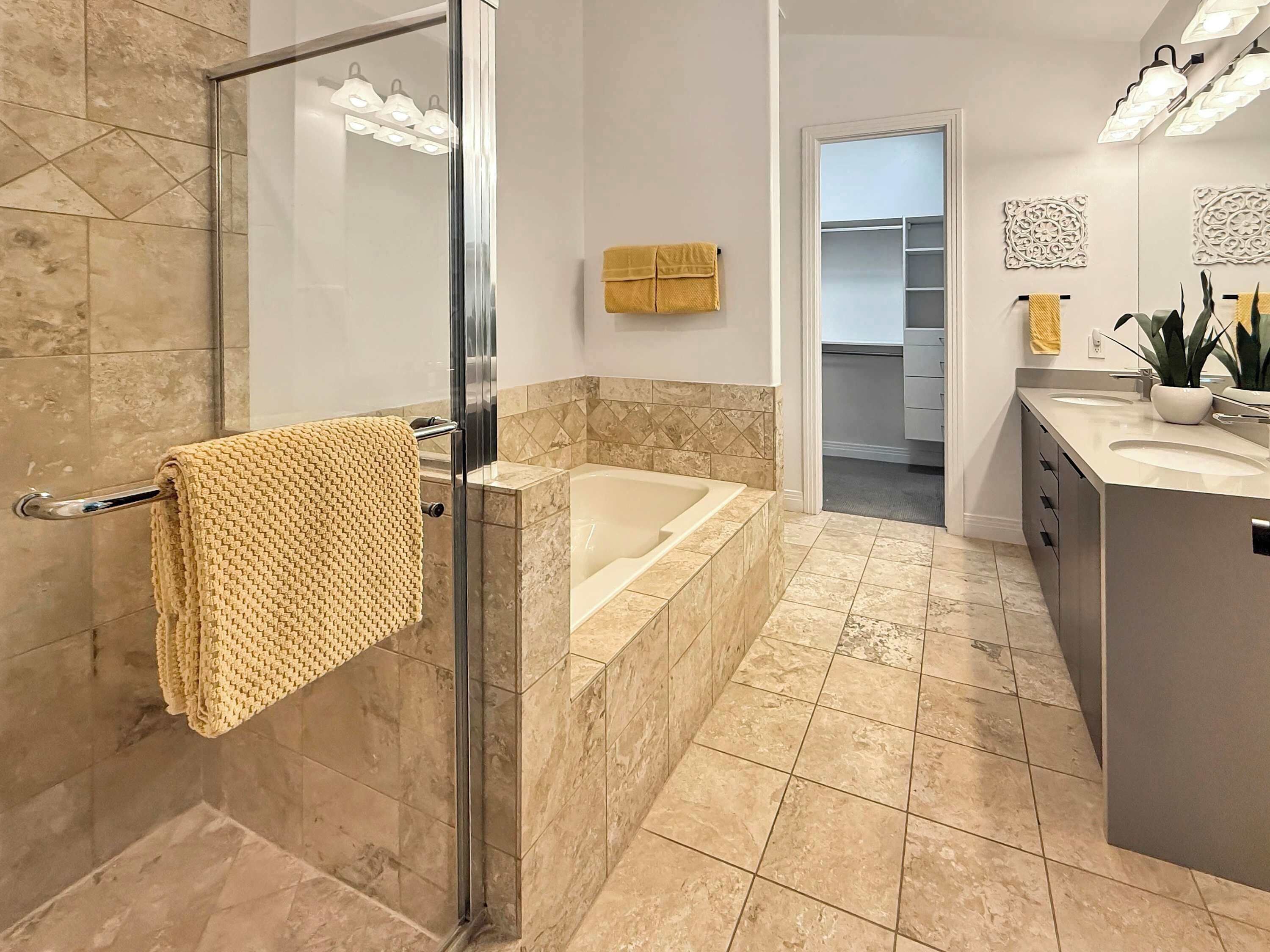 A modern bathroom with a glass shower enclosure, a bathtub, and a vanity with a sink.