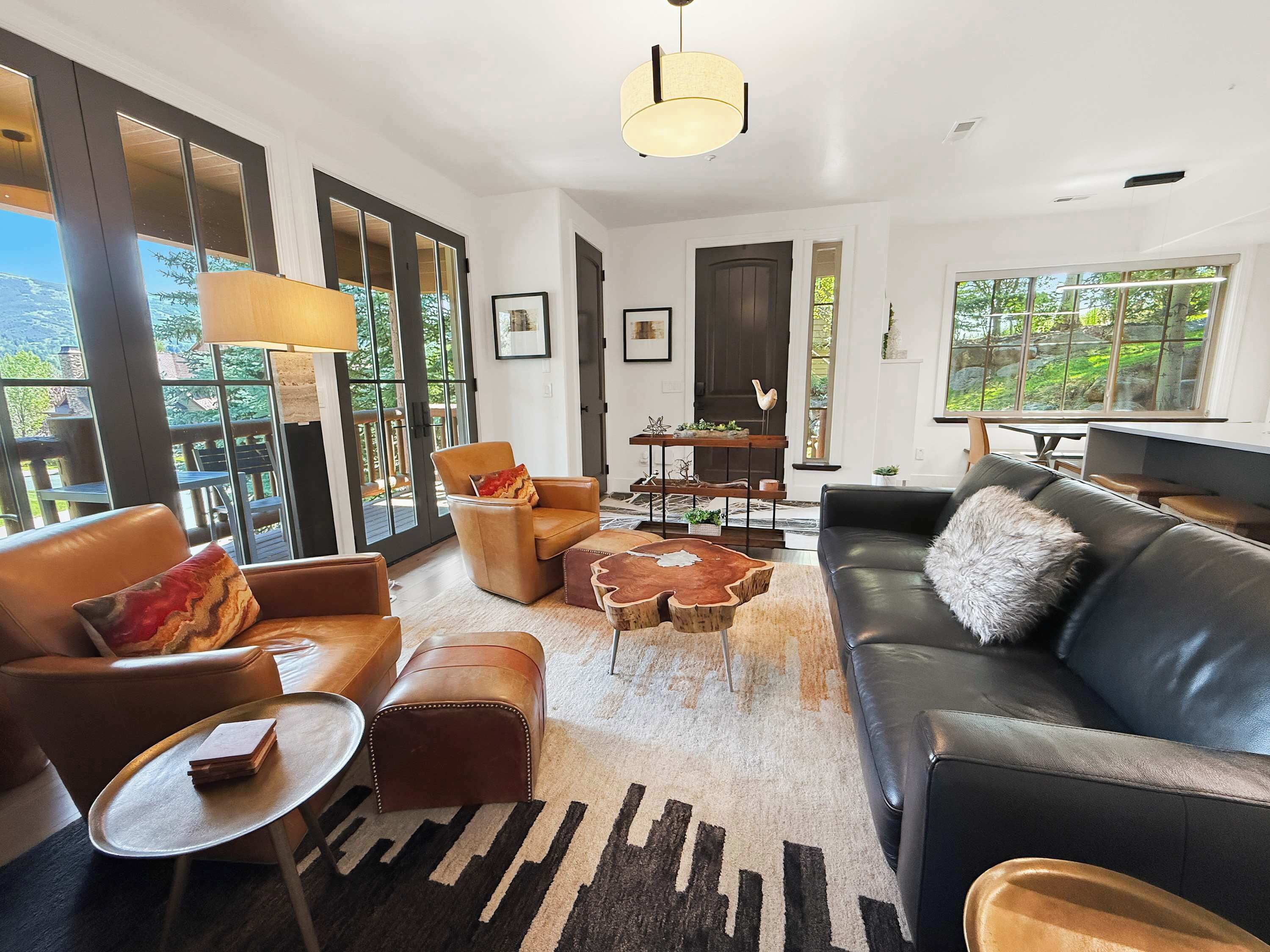 Un salon moderne avec des meubles en cuir, une grande fenêtre et une vue sur l’extérieur.