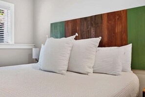 A bed with white bedding and pillows, a wooden headboard with a green panel, and a window with blinds. - Ski-In Ski-Out Blue Ridge Views at Wintergreen  Resort (Wintergreen Resort)