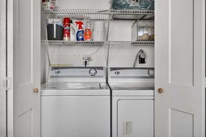 A laundry room with two washing machines, a shelf with cleaning supplies, and a faucet. - Ski-In Ski-Out Blue Ridge Views at Wintergreen  Resort (Wintergreen Resort)