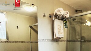 A bathroom with a double sink, a toilet, and a glass shower enclosure.