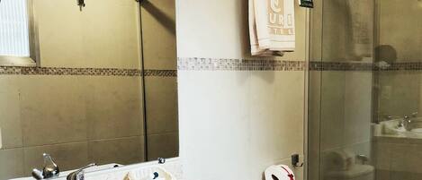 A bathroom with a double sink, a toilet, and a glass shower enclosure.
