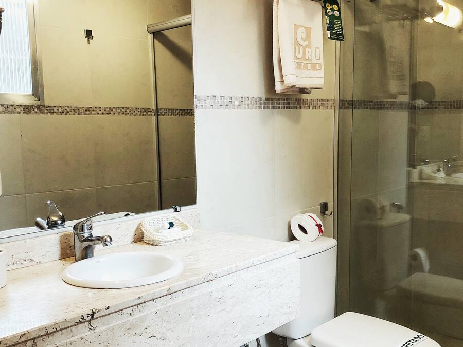A bathroom with a double sink, a toilet, and a glass shower enclosure.