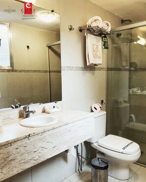A bathroom with a double sink, a toilet, and a glass shower enclosure.