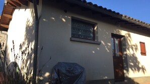 Ein Gebäude mit einem Ziegeldach, einem Fenster mit einem ornamentalen Gitter und einer Tür mit einem Holzklappladen.