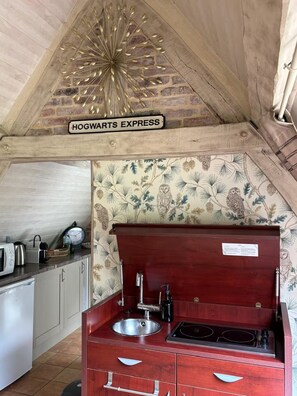 Eine Küche mit Holzboden, einem Schild mit der Aufschrift 'HOGWARTS EXPRESS' und einer Wand mit Wandpapier mit Naturmotiven.