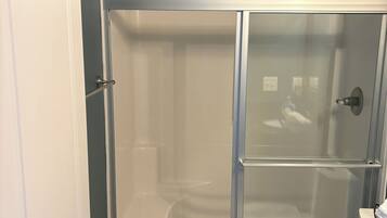 A bathroom with a glass-enclosed shower, a white toilet, and a granite countertop.