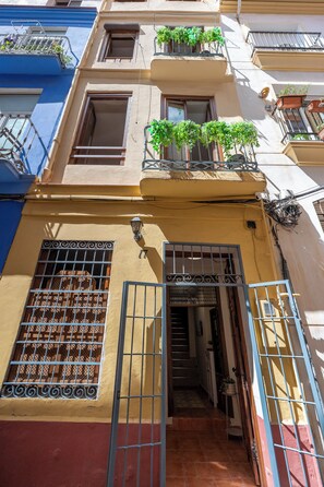 Un immeuble à plusieurs étages doté de balcons, d’une entrée sécurisée par un portail et d’un escalier menant à l’entrée.