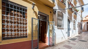A building with a yellow facade, a metal gate, and a tiled pavement. - Cozy and lovely apartment located in the historic center of Málaga. (Málaga)
