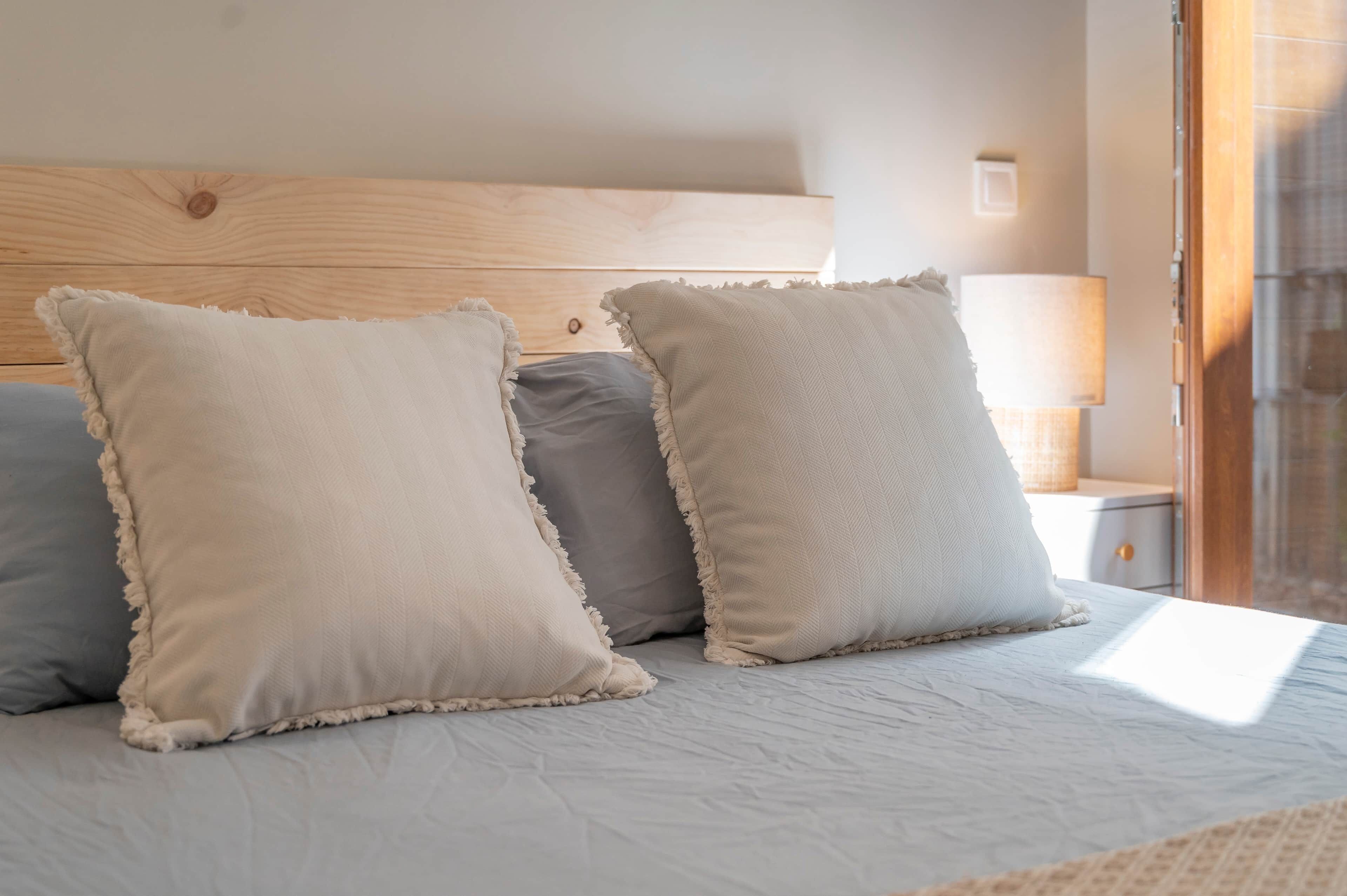 A bed with three pillows and a wooden headboard.