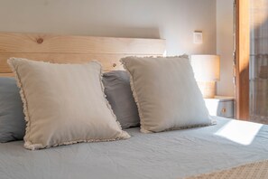 Un lit avec trois oreillers et une tête de lit en bois.