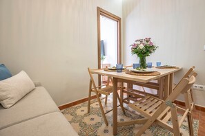 A dining area with a wooden table, chairs, and a vase of flowers. - Cozy and lovely apartment located in the historic center of Málaga. (Málaga)