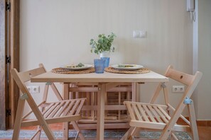 Ein Holztisch mit zwei Tellern, einem blauen Glas und einer Vase mit grünen Blättern.