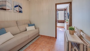 A living room with a sofa, a dining table, a hanging light fixture, and a door leading to another room. - Piso N°3 - Oliva Apartments Molinillo (Centro Histórico)