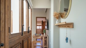 A hallway with wooden doors, a dining area with a table and chairs, a mirror on the wall, and a hanging ornament. - Cozy and lovely apartment located in the historic center of Málaga. (Centro Histórico)