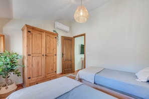 Ein Zimmer mit zwei Betten, Holzschränken, einer Klimaanlage und einer Pendelleuchte.